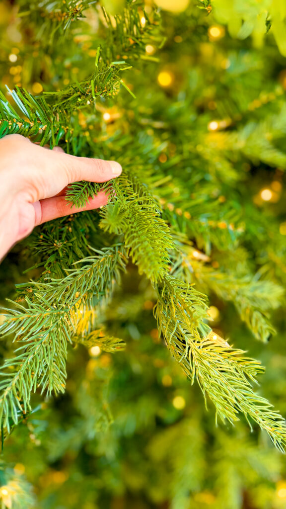 Placing additional artificial pine branch into an artificial Christmas tree.