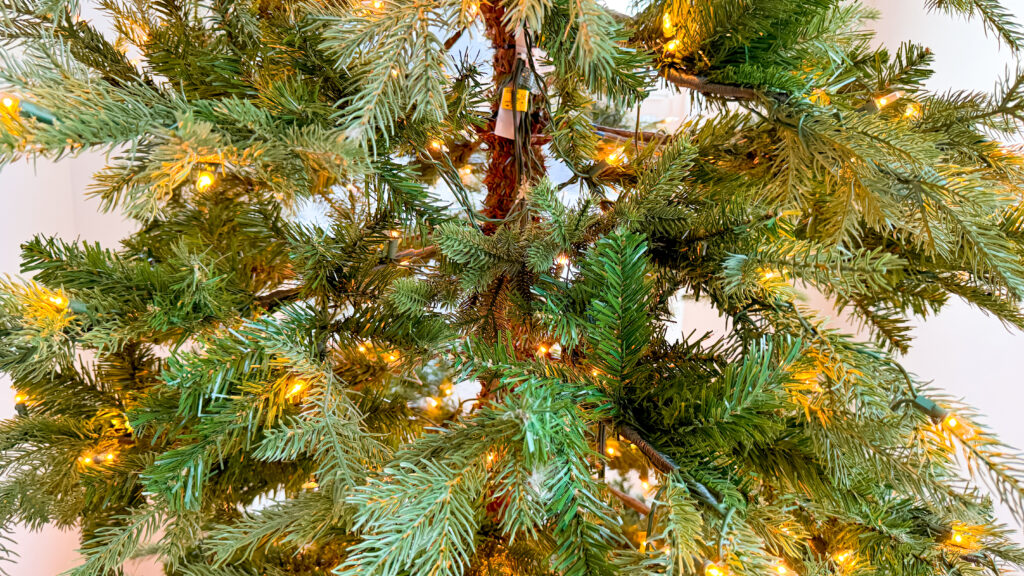 A "before" picture of the bare gaps in an artificial Christmas tree where fewer branches and pine needles than the rest of the tree.