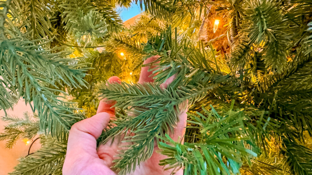 An "after" photo of an artificial Christmas tree, where the bare spots and gaps in the branches have been filled in with additional artificial pine branches.
